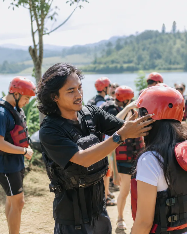 Tim lapangan BumiSelatan membantu peserta memakai helm sebelum rafting